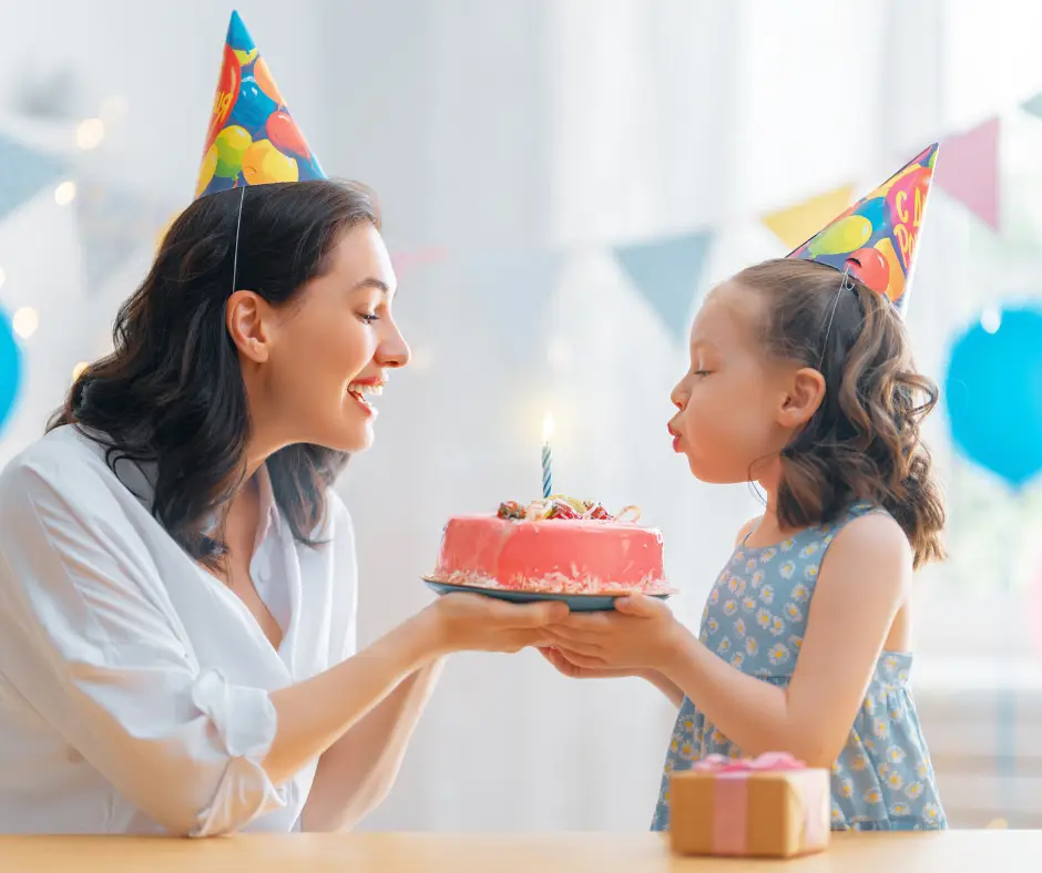 Daughter blowing her birthday cake with her mother