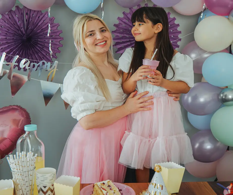 mom. and daughter celebrate birthday party with balloons and cake and favours