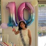 birthday girl posing with drink and a 10 behind her